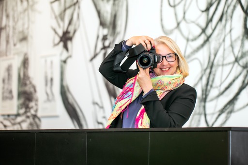 Cherry the photographer pointing the camera at the viewer smiling at the camera